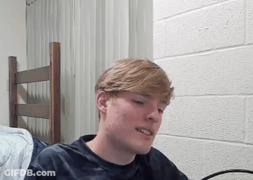 Young Man Sitting In Front Of Brick Wall GIF