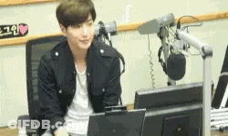 A Young Man Is Sitting In Front Of A Microphone In Front Of A Computer Monitor .. GIF