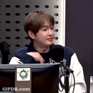 A Young Man Is Sitting In Front Of A Microphone In Front Of A Computer Monitor . GIF