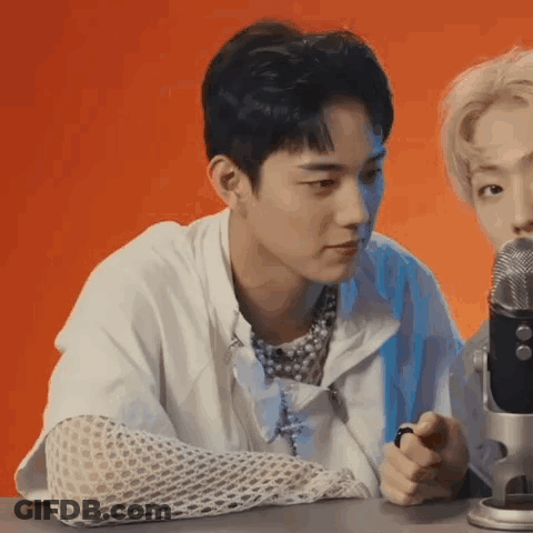 A Young Man Is Sitting In Front Of A Microphone . GIF