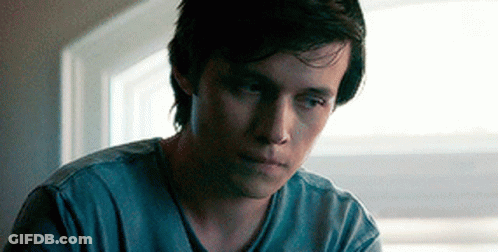 A Young Man Is Sitting In Front Of A Window Looking Down . GIF