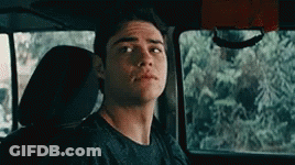 A Young Man Is Sitting In The Back Seat Of A Car Looking At The Camera . GIF