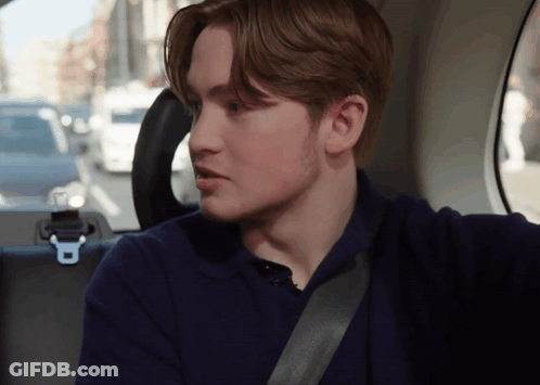 A Young Man Is Sitting In The Back Seat Of A Car With A Seat Belt Around His Neck GIF