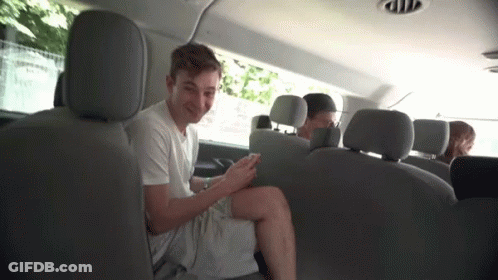 A Young Man Is Sitting In The Back Seat Of A Van Looking At His Cell Phone . GIF