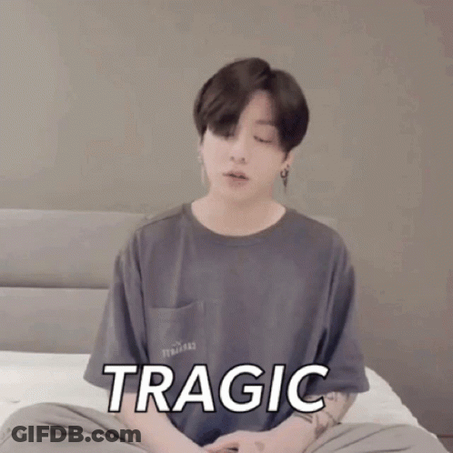 A Young Man Is Sitting On A Bed With His Eyes Closed And The Word Tragic On His Shirt GIF