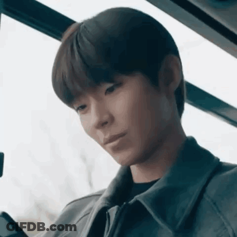A Young Man Is Sitting On A Bus And Looking At His Phone . GIF