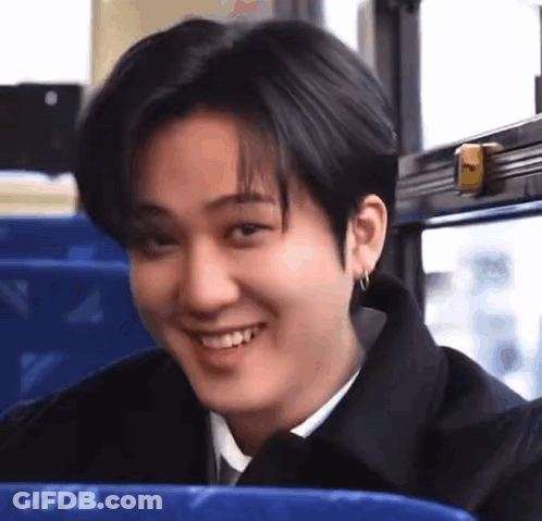 A Young Man Is Sitting On A Bus Smiling . GIF