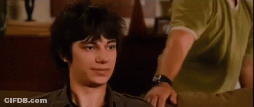 A Young Man Is Sitting On A Couch And Looking At The Camera . GIF