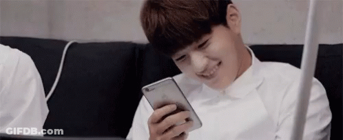 A Young Man Is Sitting On A Couch Using A Cell Phone . GIF