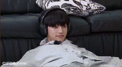 A Young Man Is Sitting On A Couch Wearing Headphones And A Poncho . GIF