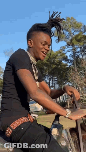 A Young Man Is Sitting On A Motorcycle In The Woods . GIF