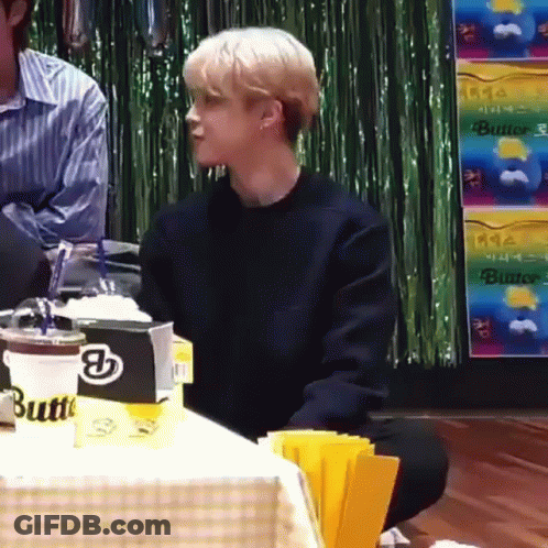 A Young Man Is Sitting On The Floor In Front Of A Table With A Cup Of Coffee . GIF