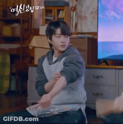 A Young Man Is Sitting On The Floor In Front Of A Television Holding A Piece Of Paper . GIF