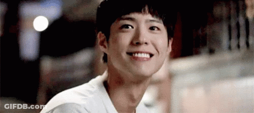A Young Man Is Smiling And Looking At The Camera While Sitting At A Table . GIF