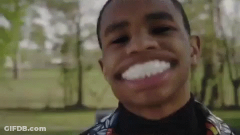 A Young Man Is Smiling And Making A Funny Face In A Park With Trees In The Background . GIF