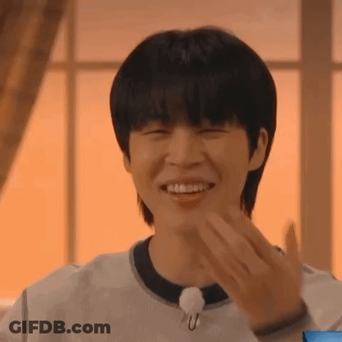 A Young Man Is Smiling And Making A Funny Face While Wearing A White Shirt . GIF
