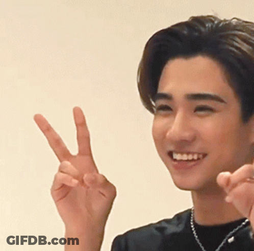 A Young Man Is Smiling And Making A Peace Sign With His Hand GIF