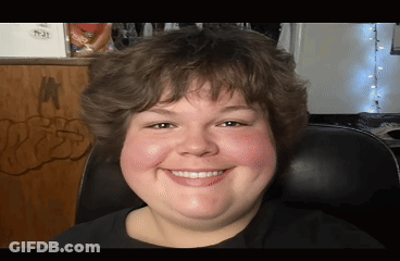 A Young Man Is Smiling And Sitting In A Chair GIF