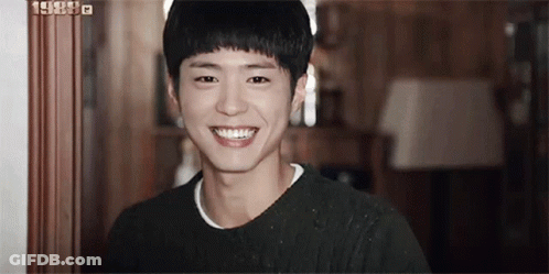 A Young Man Is Smiling For The Camera In A Room . GIF