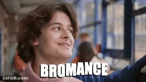 A Young Man Is Smiling In Front Of A Window And The Word Bromance Is Above Him GIF
