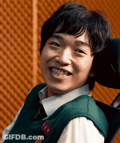 A Young Man Is Smiling While Sitting In A Wheelchair . GIF