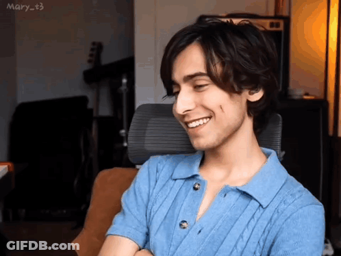 A Young Man Is Smiling While Sitting In An Office Chair . GIF