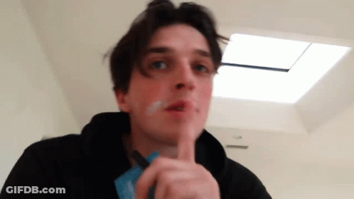 A Young Man Is Smoking A Cigarette In A Room With A Skylight . GIF