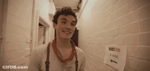 A Young Man Is Standing In A Hallway Next To A Sign That Says Slowing . GIF