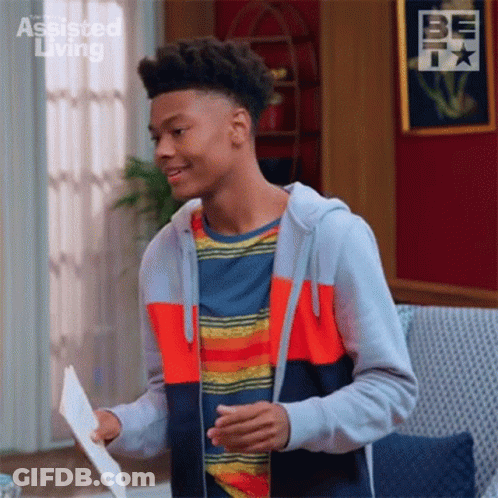 A Young Man Is Standing In A Living Room Holding A Piece Of Paper In His Hand . GIF