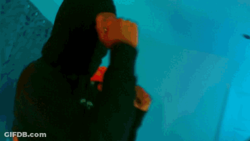 A Young Man Is Standing In A Room Wearing A Black Leather Jacket And A Red Hoodie . GIF
