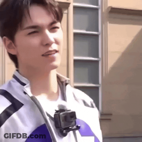 A Young Man Is Standing In Front Of A Building With A Gopro Camera Attached To His Neck . GIF