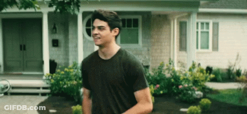 A Young Man Is Standing In Front Of A House . GIF