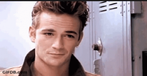 A Young Man Is Standing In Front Of A Locker And Looking At The Camera . GIF