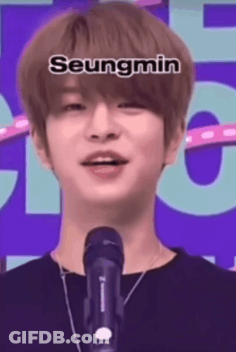 A Young Man Is Standing In Front Of A Microphone And Talking Into It . GIF