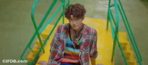 A Young Man Is Standing In Front Of A Palm Tree And Looking At The Camera . GIF