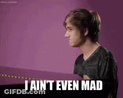 A Young Man Is Standing In Front Of A Purple Wall And Says `` I Ain 'T Even Mad '' . GIF