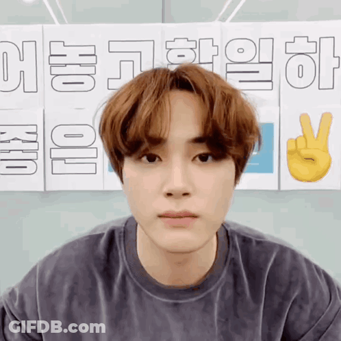 A Young Man Is Standing In Front Of A Sign That Says ' Korean ' On It GIF