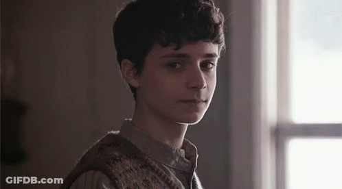 A Young Man Is Standing In Front Of A Window In A Dark Room . GIF