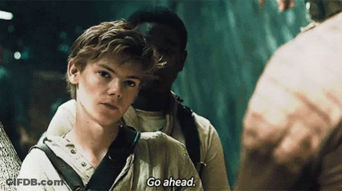 A Young Man Is Standing Next To Another Young Man And Talking To Him . GIF