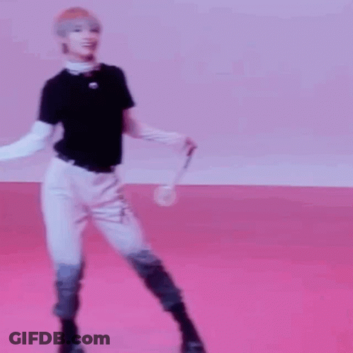 A Young Man Is Standing On A Pink Floor Holding A Microphone . GIF