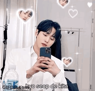 A Young Man Is Taking A Selfie In Front Of A Mirror With His Phone . GIF