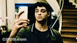 A Young Man Is Taking A Selfie With His Cell Phone In Front Of Stairs . GIF