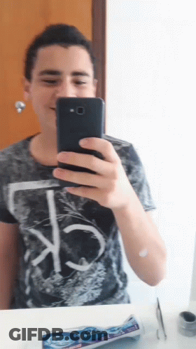 A Young Man Is Taking A Selfie With His Phone In Front Of A Mirror GIF