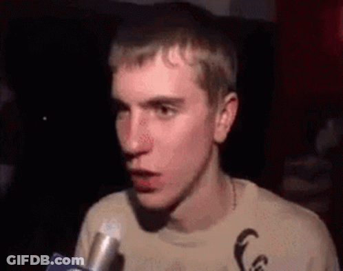 A Young Man Is Talking Into A Microphone While Making A Funny Face . GIF