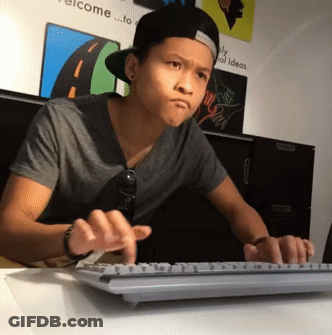 A Young Man Is Typing On A Keyboard In Front Of A Wall That Says Welcome GIF