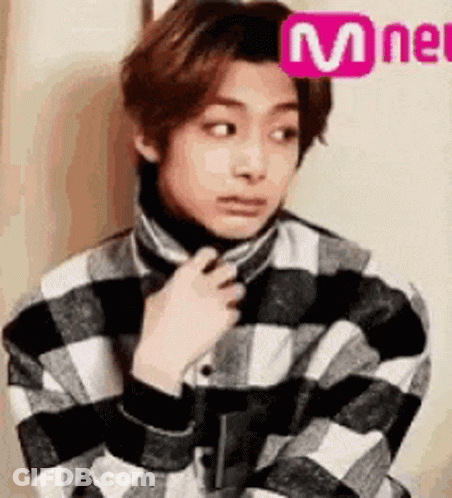 A Young Man Is Wearing A Plaid Shirt And A Turtleneck Sweater . GIF