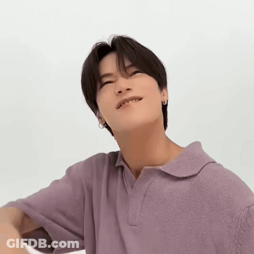 A Young Man Is Wearing A Purple Polo Shirt And Looking Up At The Camera . GIF