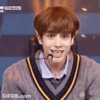 A Young Man Is Wearing A Sweater And A Microphone . GIF