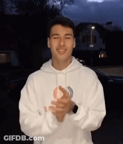 A Young Man Is Wearing A White Hoodie And Clapping His Hands . GIF