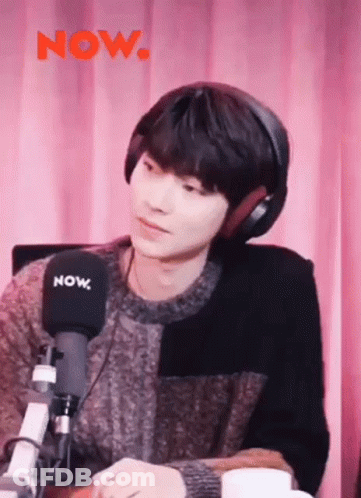 A Young Man Is Wearing Headphones And Sitting In Front Of A Microphone . GIF